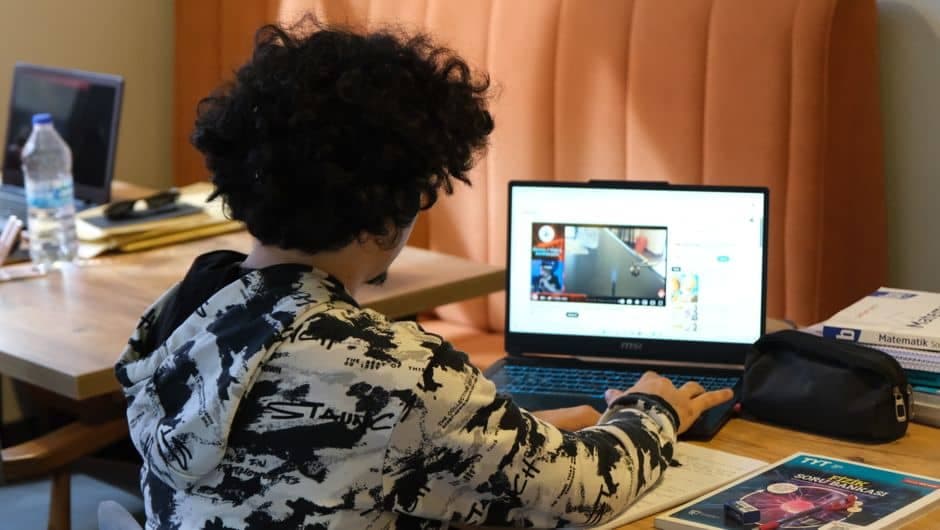 Jovem estudando em casa com notebook e livros
