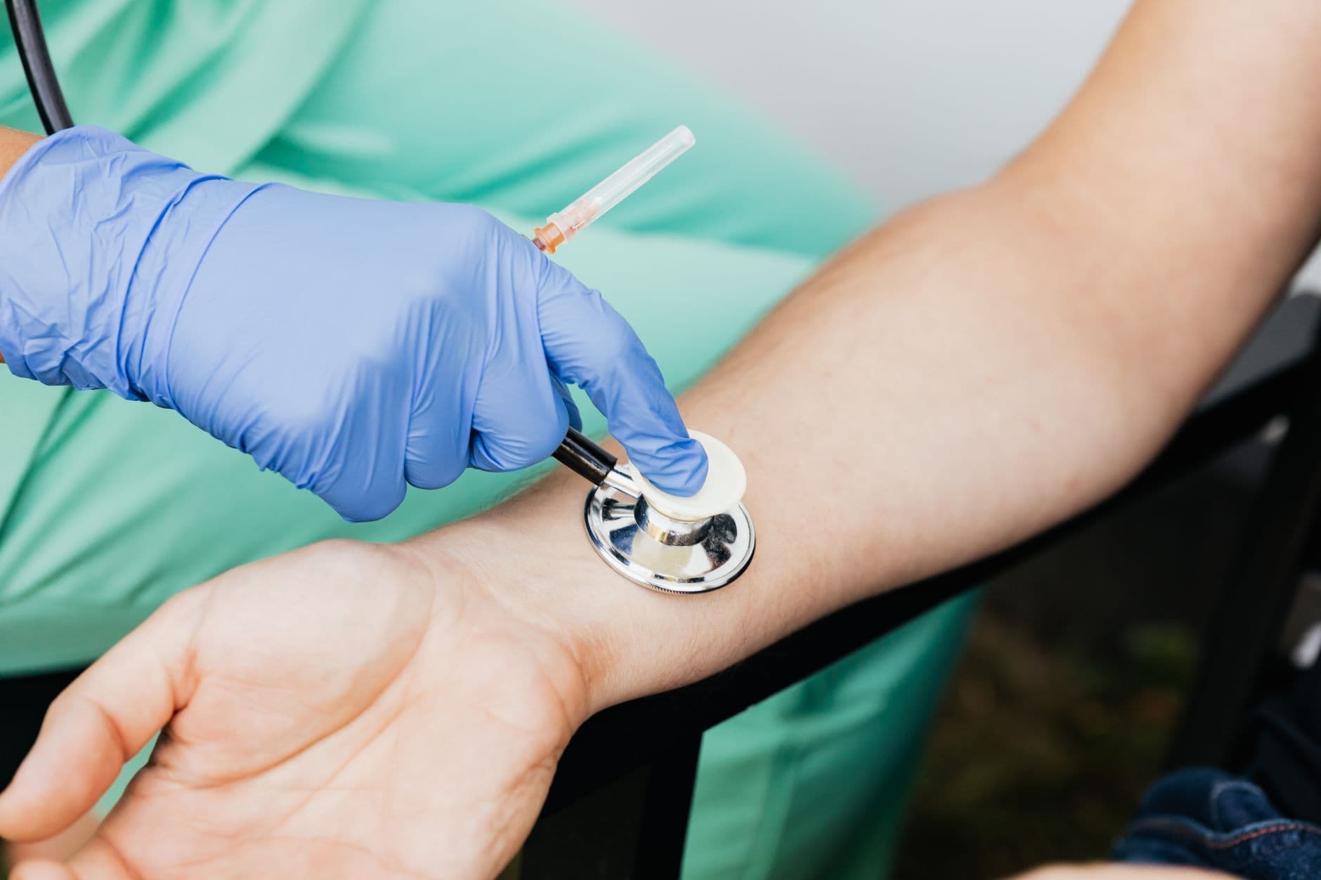 Acidente de trabalho em home office: você está protegido? Healthcare professional using a stethoscope on patient's wrist during a medical exam.