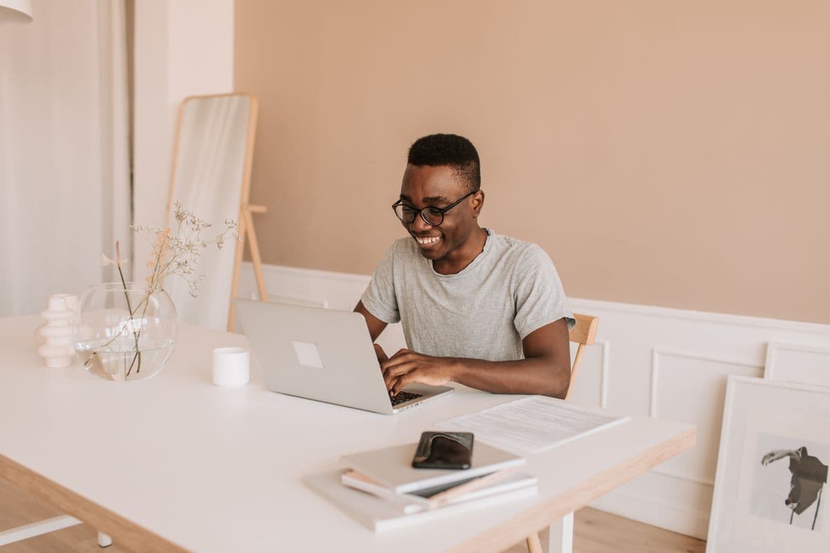 Pessoa trabalhando em um notebook em uma mesa de home office com proteção digital na tela.