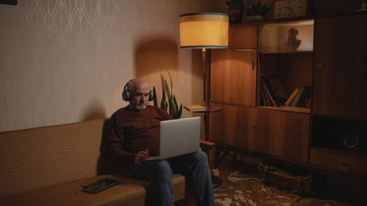 Homem trabalhando no notebook no sofá de um apartamento aconchegante