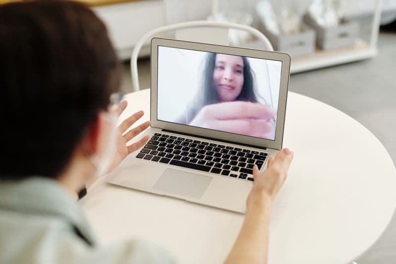 Body doubling: como trabalhar acompanhado em casa A person having a video call on a laptop, indoors, showcasing digital communication.