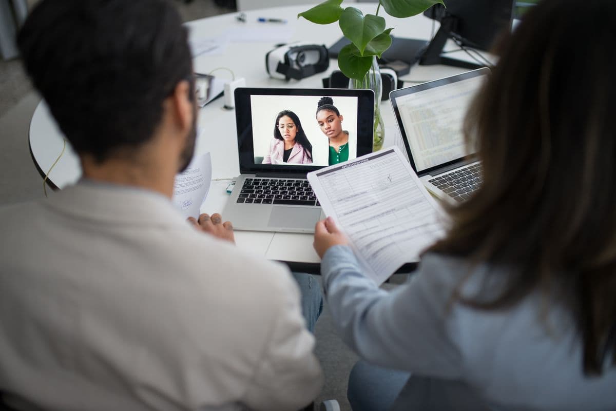 Profissionais remotos analisando uma agenda compartilhada em laptops durante uma videoconferência