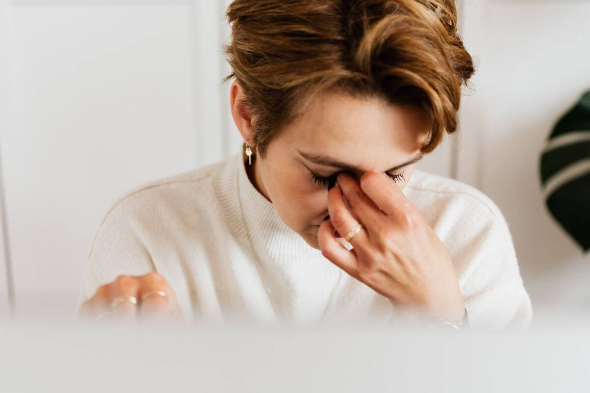 Mulher esfregando os olhos cansados diante do computador