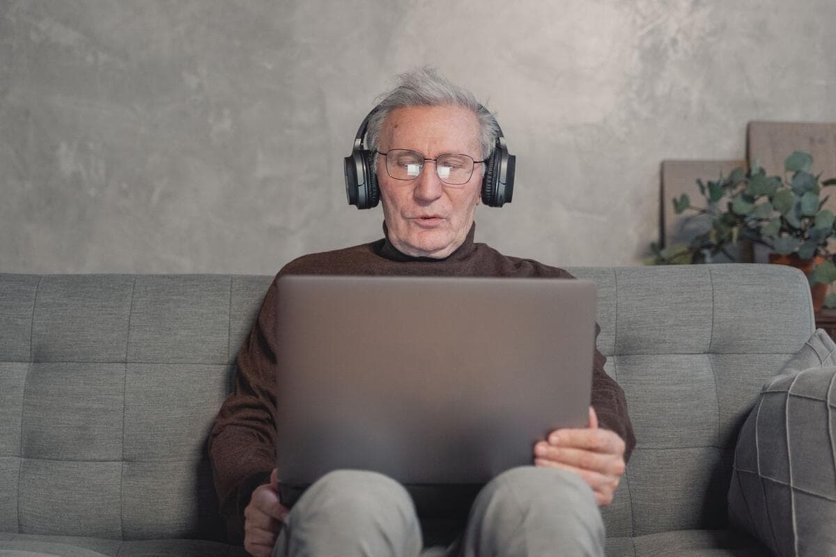 Como dividir o espaço quando não há dois escritórios Homem com fone de ouvido trabalhando no notebook sentado no sofá