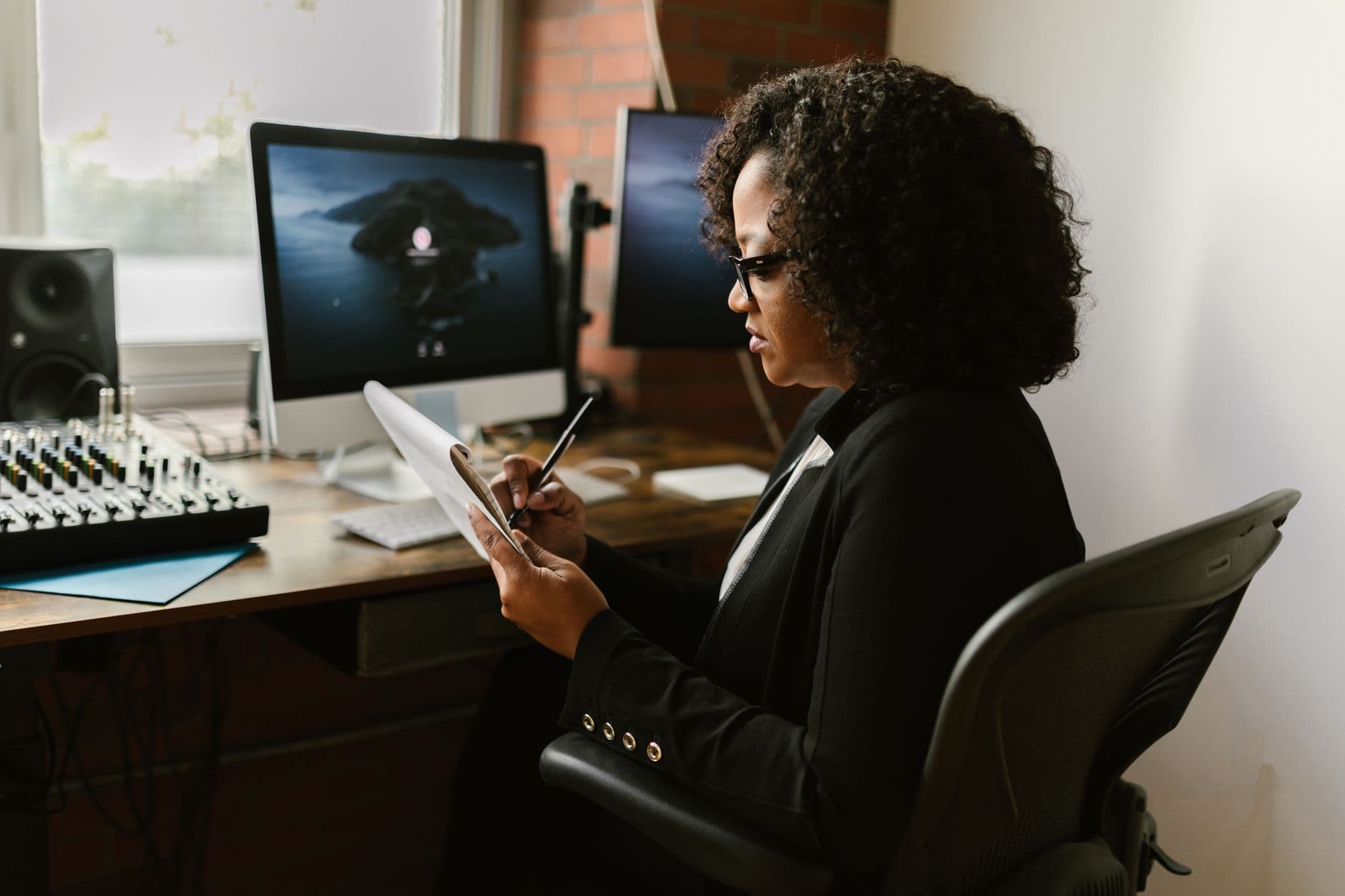 Certificações que valorizam seu currículo para vagas remotas Confident businesswoman writing notes while working in a modern office setting.