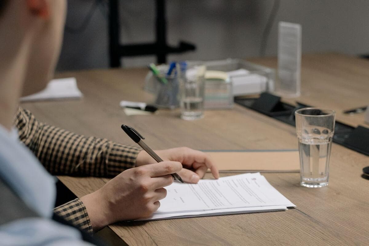 Pessoa de terno assinando um contrato sobre uma mesa de madeira