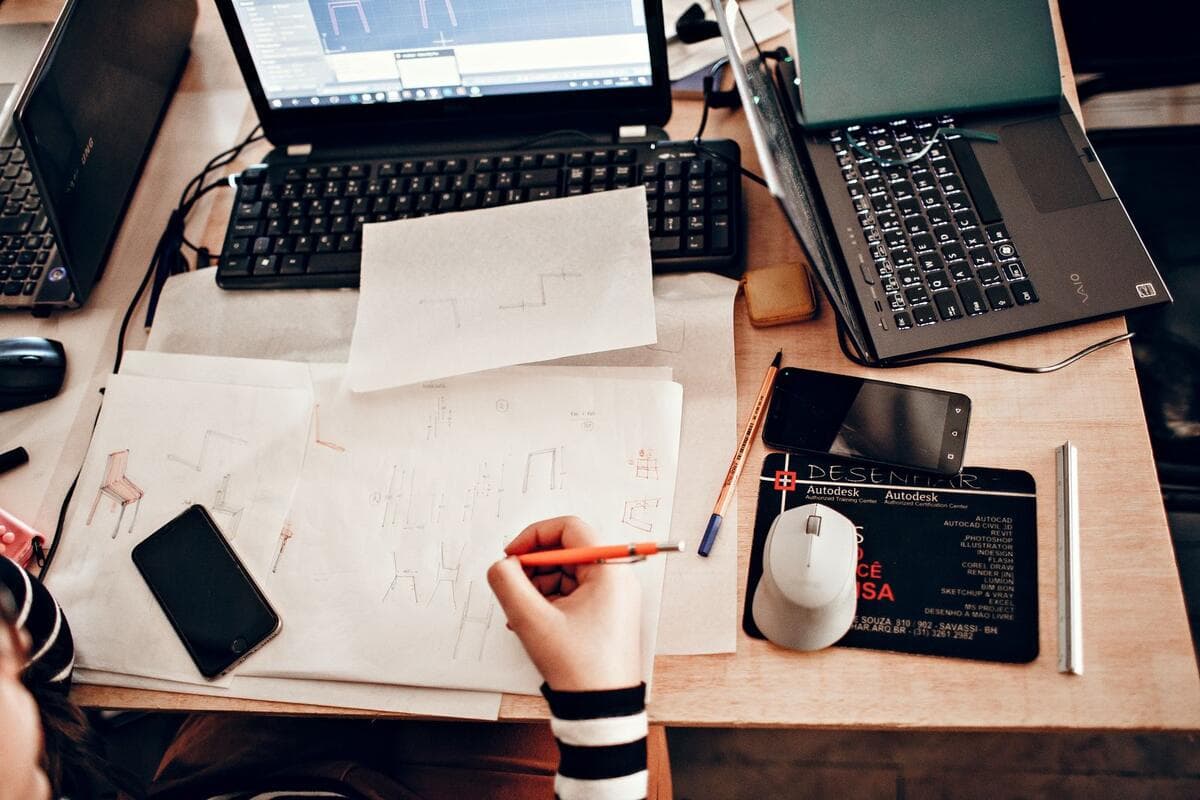 O que colocar no contrato e na proposta Mesa de trabalho com esboços e anotações de revisões de um projeto