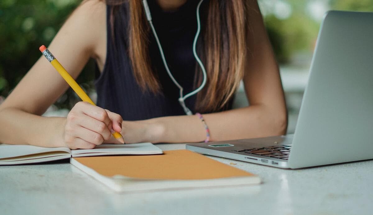 Como encerrar um projeto que já saiu do controle Profissional fazendo anotações em um caderno ao lado do notebook