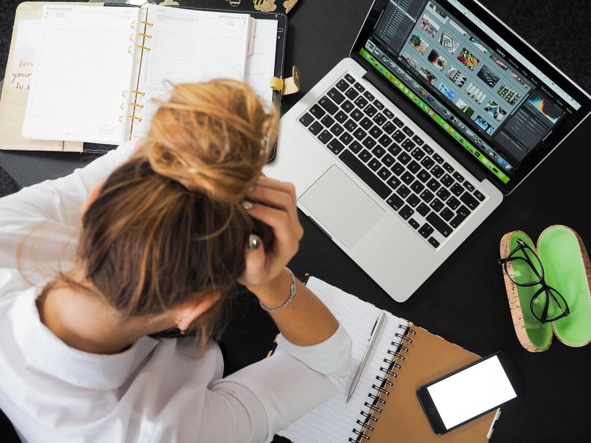 Freelancer com as mãos na cabeça diante do notebook, frustrada com um projeto