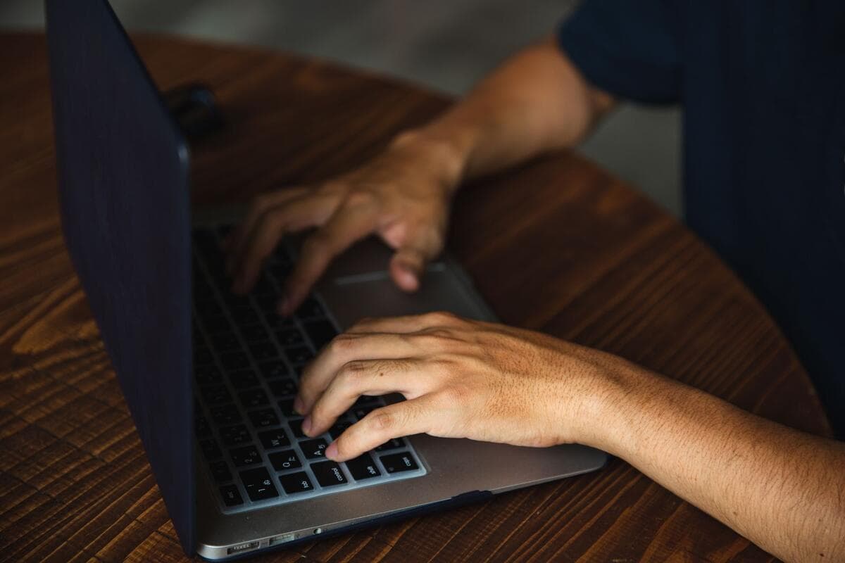 Profissional trabalhando no notebook em mesa redonda, escrevendo mensagem para a equipe