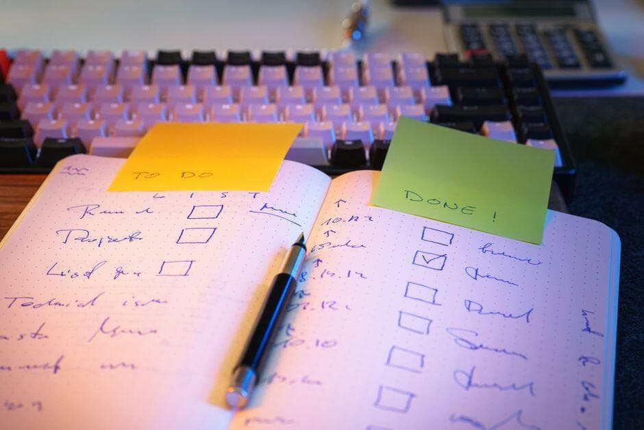 Caderno aberto com lista de tarefas marcadas sobre a mesa de trabalho