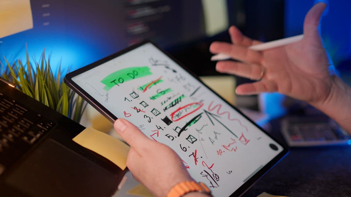 Freelancer trabalhando no laptop enquanto organiza prazos em uma mesa de home office
