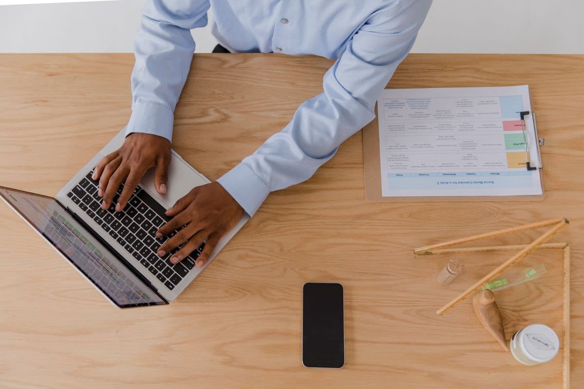 Pessoa trabalhando em uma mesa de home office limpa e organizada com notebook e acessórios