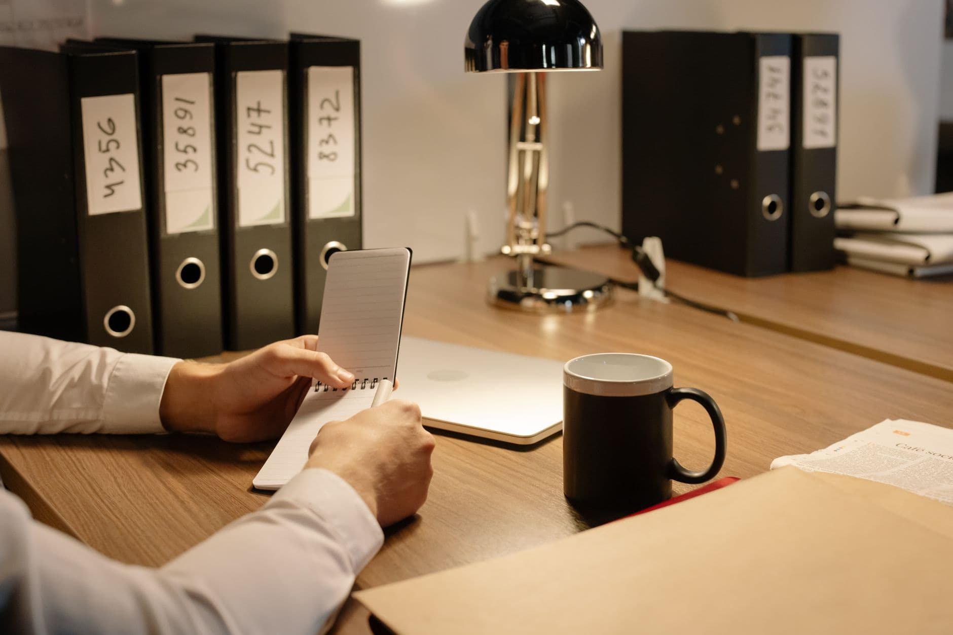 Pessoa organizando documentos digitais em um notebook sobre uma mesa de home office