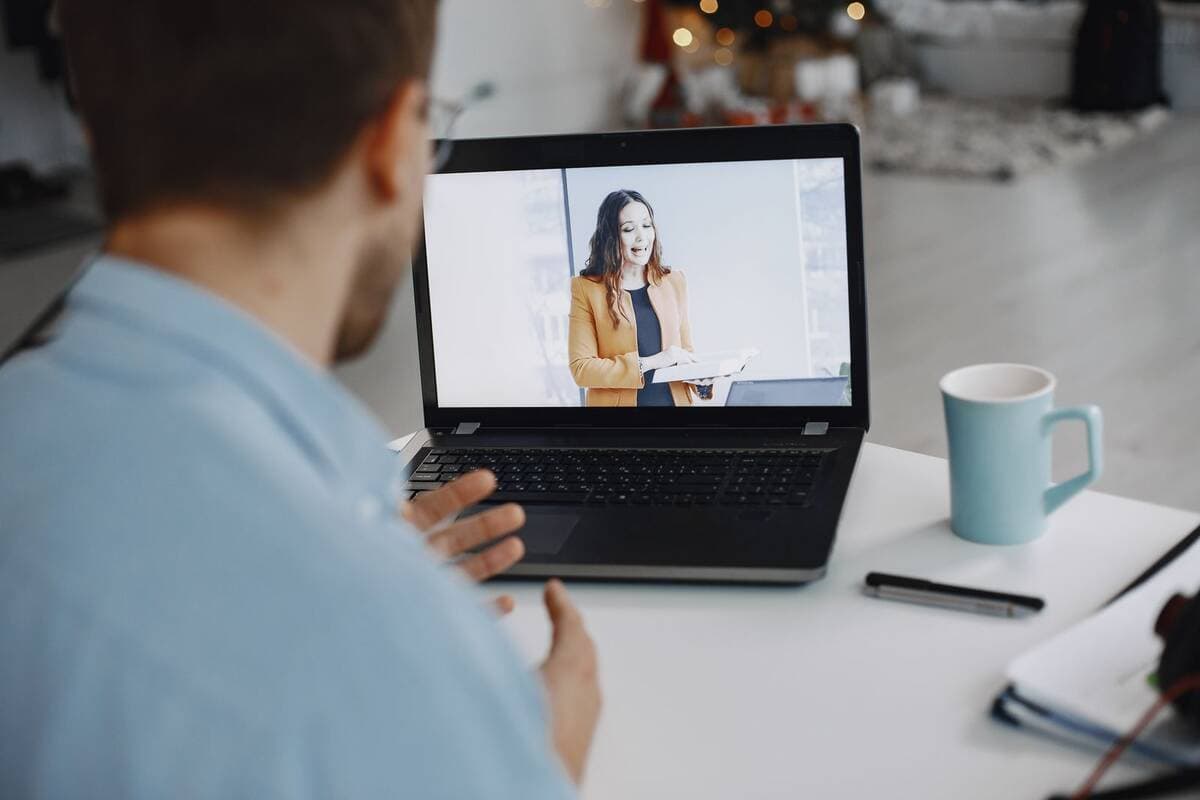 Homem em videochamada com colega pelo notebook em casa