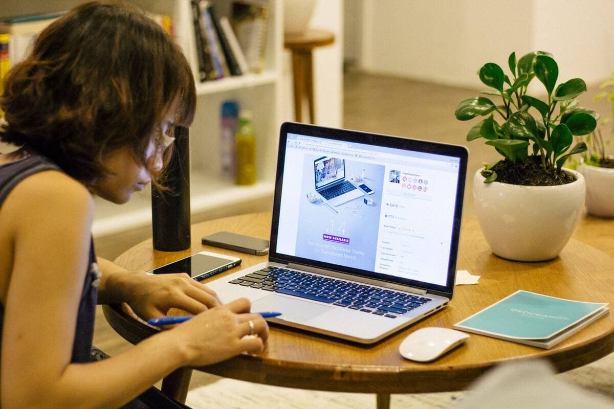 Mulher trabalhando em casa com notebook e planta na mesa