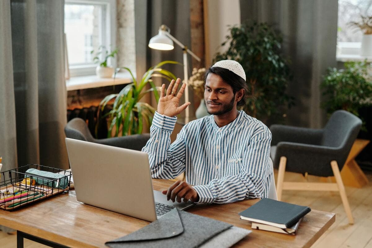 Freelancer acenando para cliente em chamada de vídeo no home office