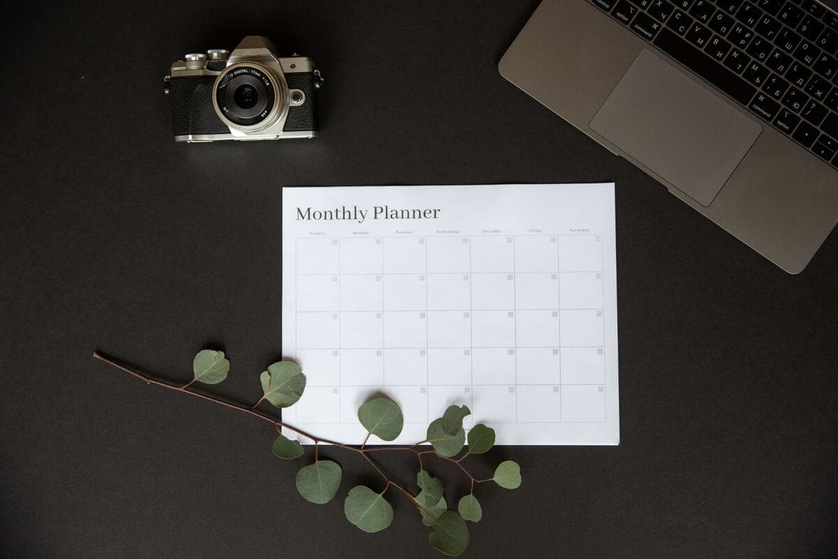 Os três formatos de retainer mais usados Planner mensal aberto ao lado do notebook, usado para planejar horas de um contrato de retainer