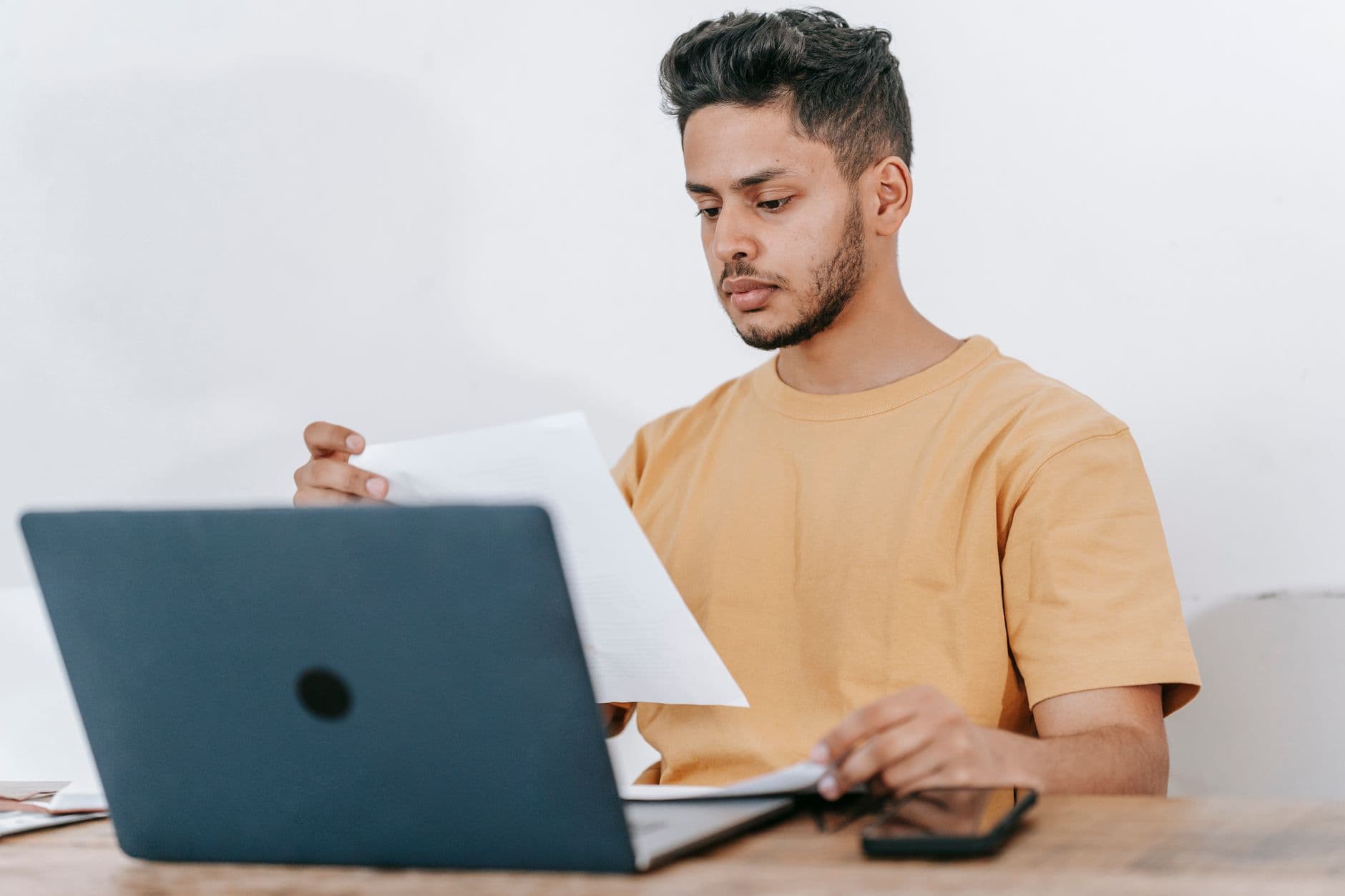 Pessoa revisando um currículo em um laptop sobre a mesa de home office