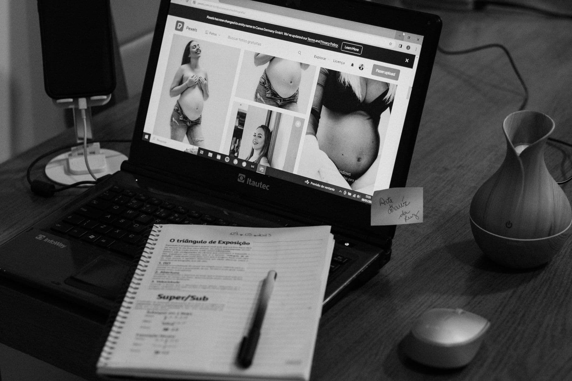 Pessoa estudando em computador portátil em uma mesa de trabalho organizada em casa.