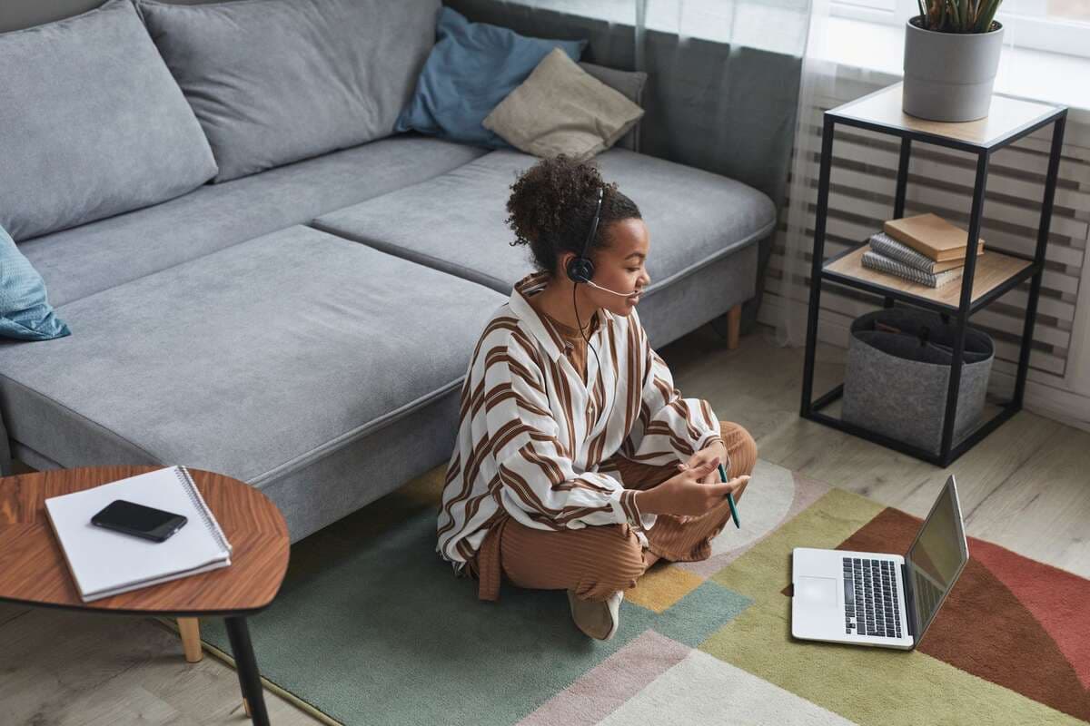 Regras simples que mantêm a daily curta Mulher com headset trabalhando no notebook sentada no chão da sala
