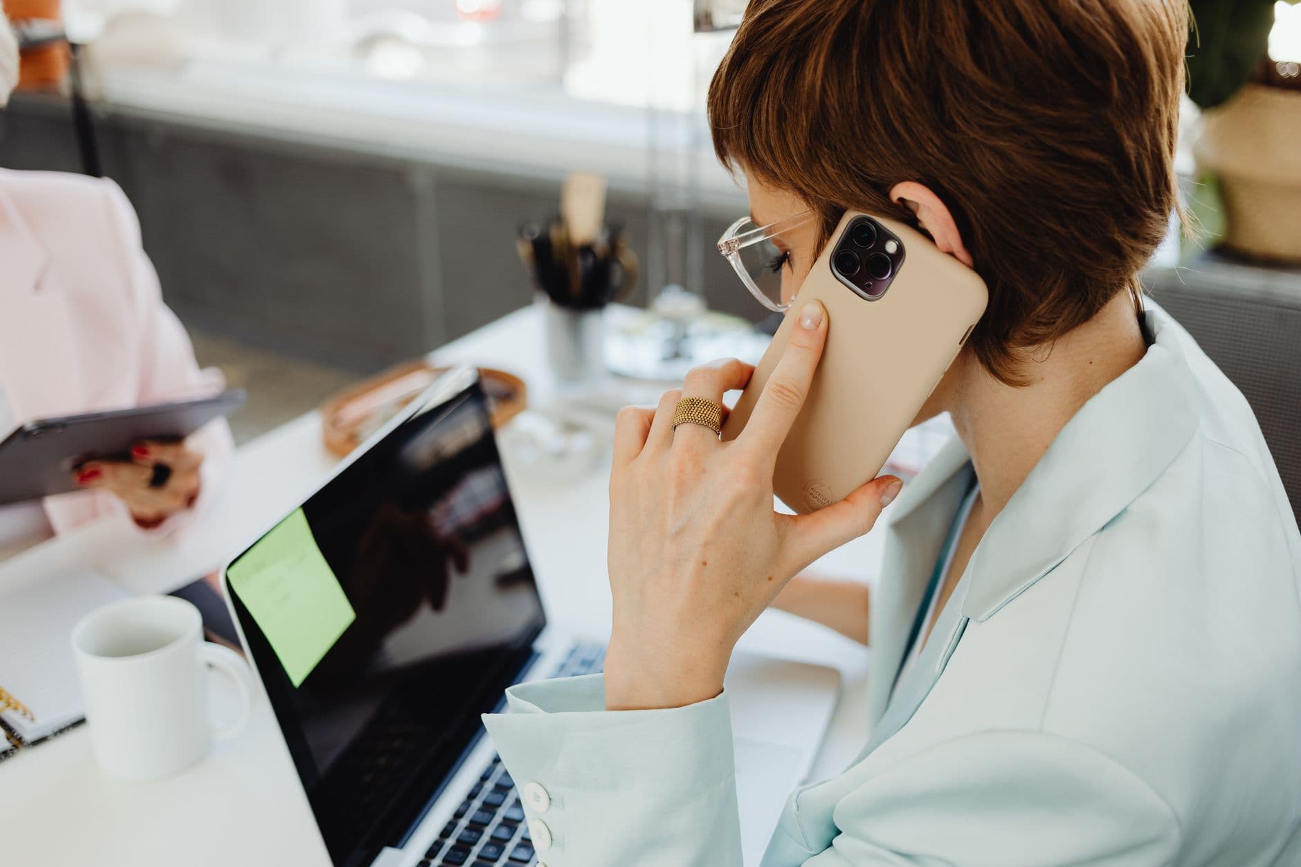 Direito à desconexão no home office existe? A businesswoman multitasking between a smartphone and laptop in an office setting efficiently.