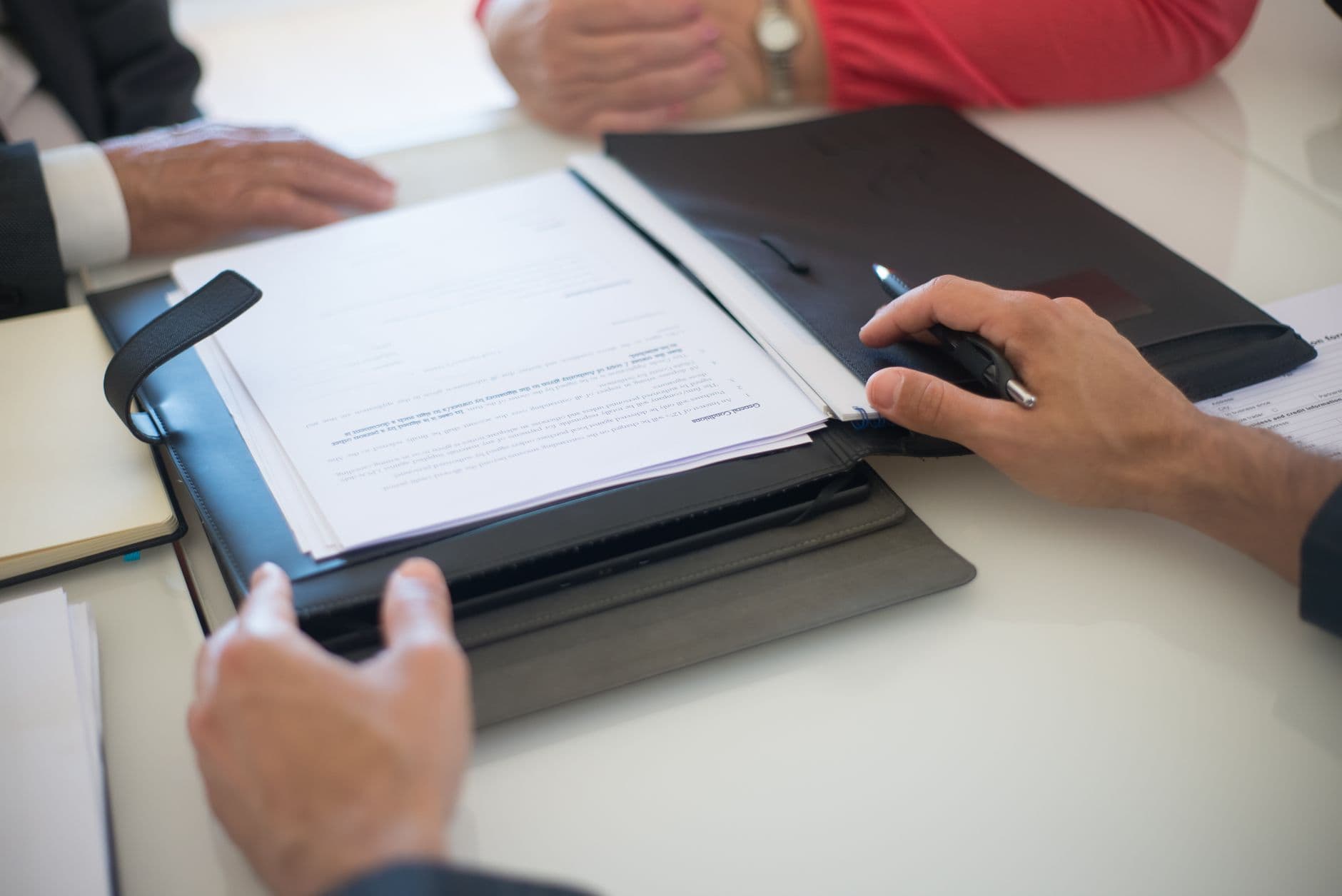 Empresa pode obrigar a volta ao escritório? Two professionals discussing a contract with documents on a table, indoors.