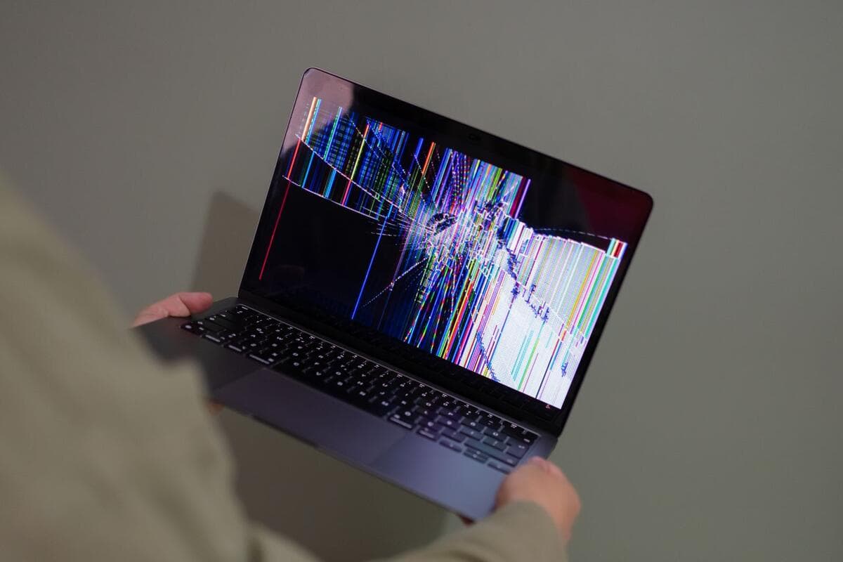 Quando a empresa pode descontar do salário Pessoa segurando notebook com a tela quebrada