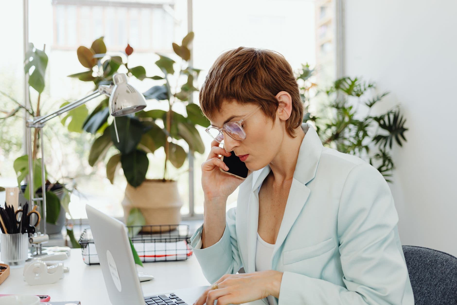 Ferramentas de foco e bloqueio de distração Businesswoman in a light suit working on laptop, talking on phone in office.