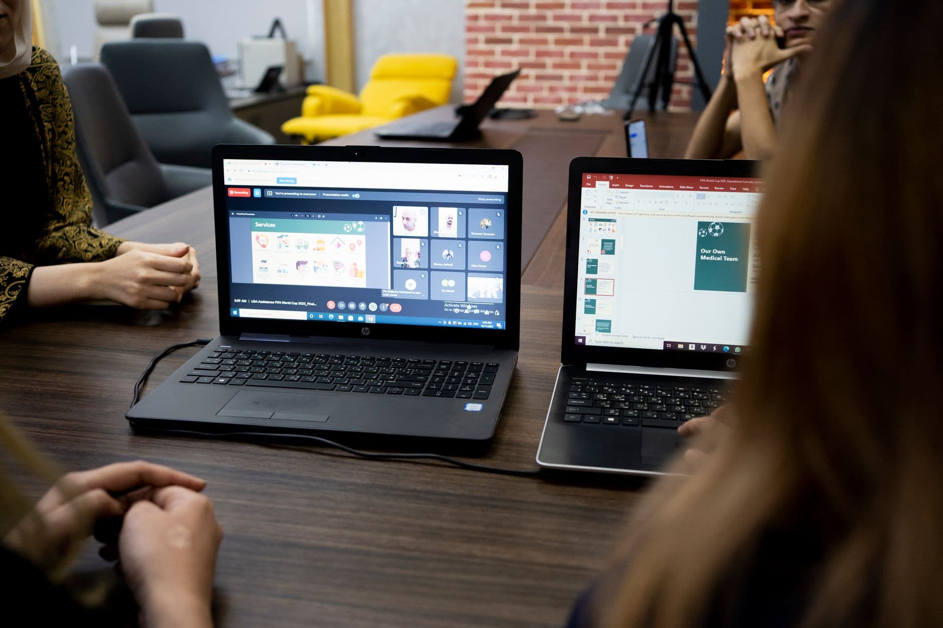 Ferramentas de gestão de tarefas para equipe remota Team discusses projects during a virtual and in-person meeting in a Dubai office.
