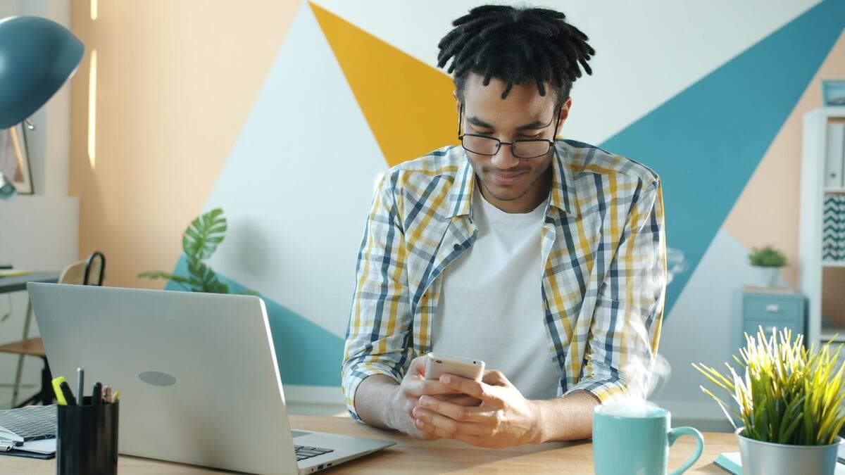 O que escrever em cada contato Freelancer conferindo mensagens no celular ao lado do notebook
