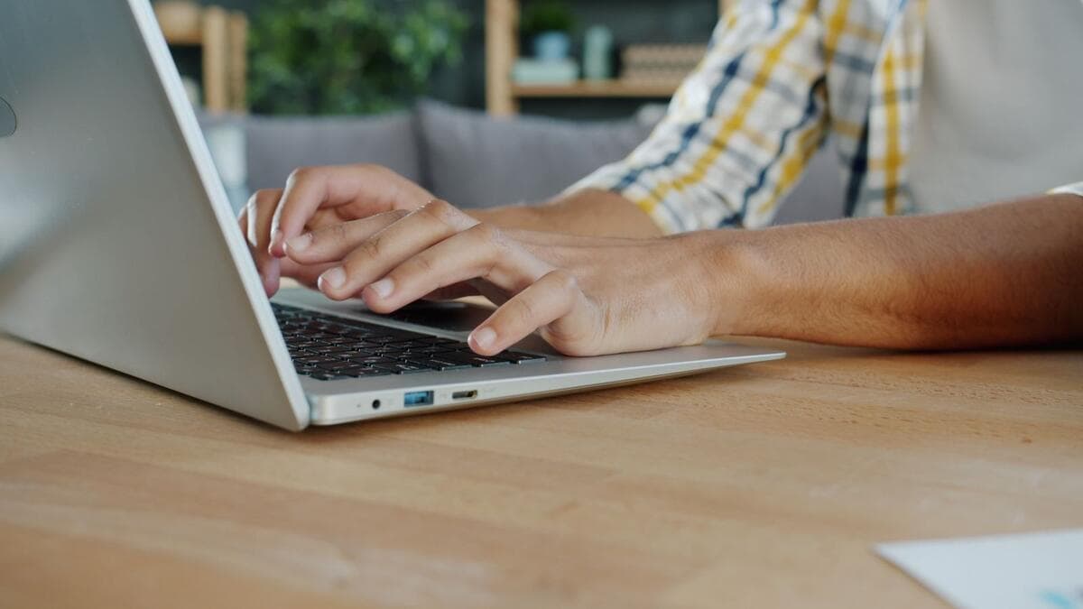Mãos digitando uma mensagem no notebook sobre a mesa