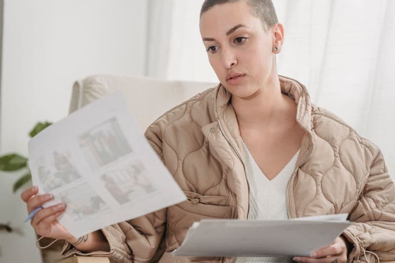 Freelancer: como se planejar para a aposentadoria A bald woman focuses on reviewing papers indoors, showcasing a professional setting.