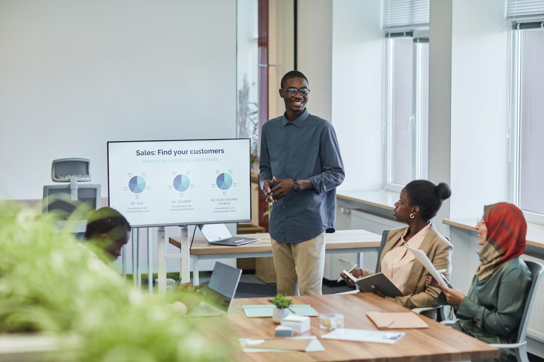 Freelancer de design UX/UI: como começar A diverse team having a corporate meeting with a sales presentation in a modern office setting.