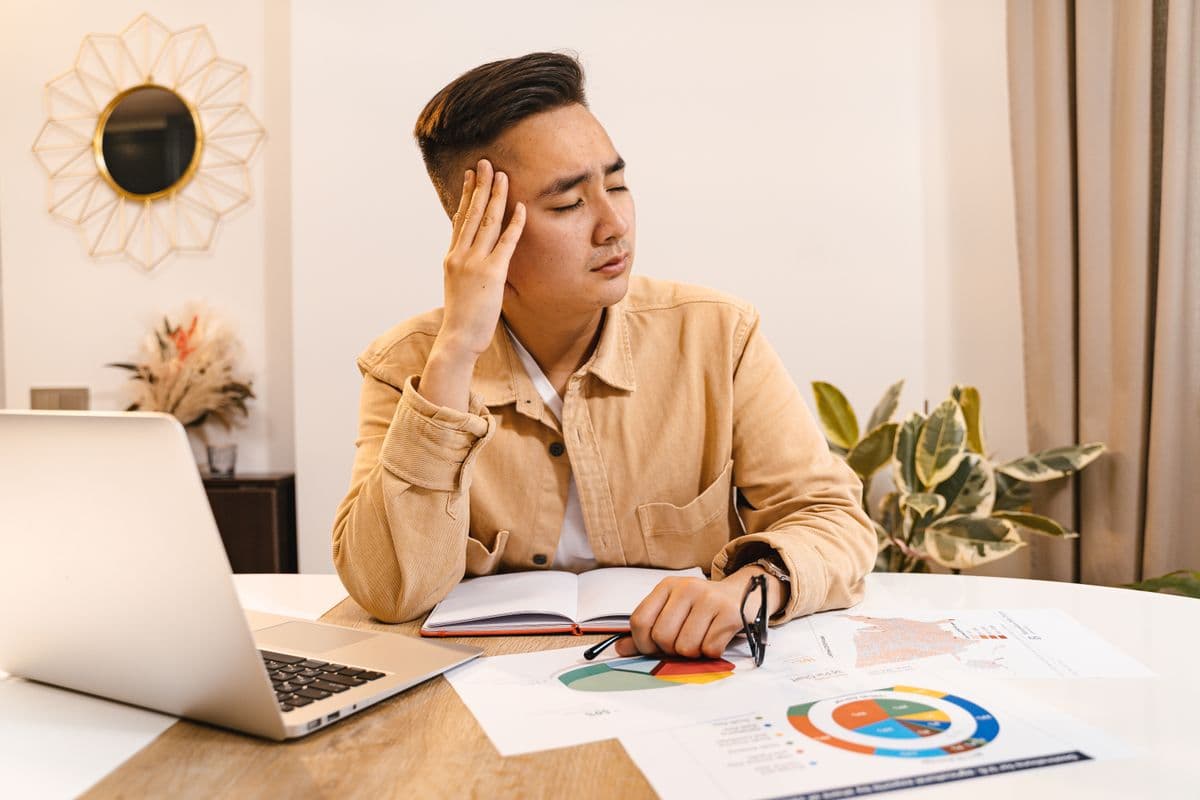 Freelancer analisando documentos financeiros ao lado de um notebook em casa