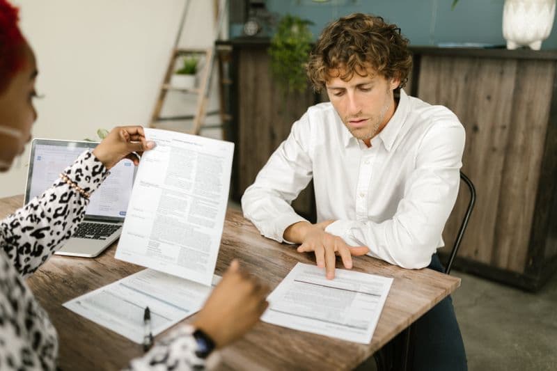 Freelancer e limite do MEI: o que fazer ao estourar Two professionals reviewing documents in an office setting, focused on analytical tasks.