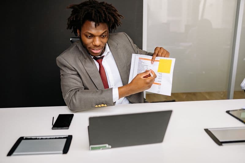 Freelancer: como definir um escopo fechado e evitar retrabalho Businessman in formal attire presenting documents during an online meeting using a laptop.