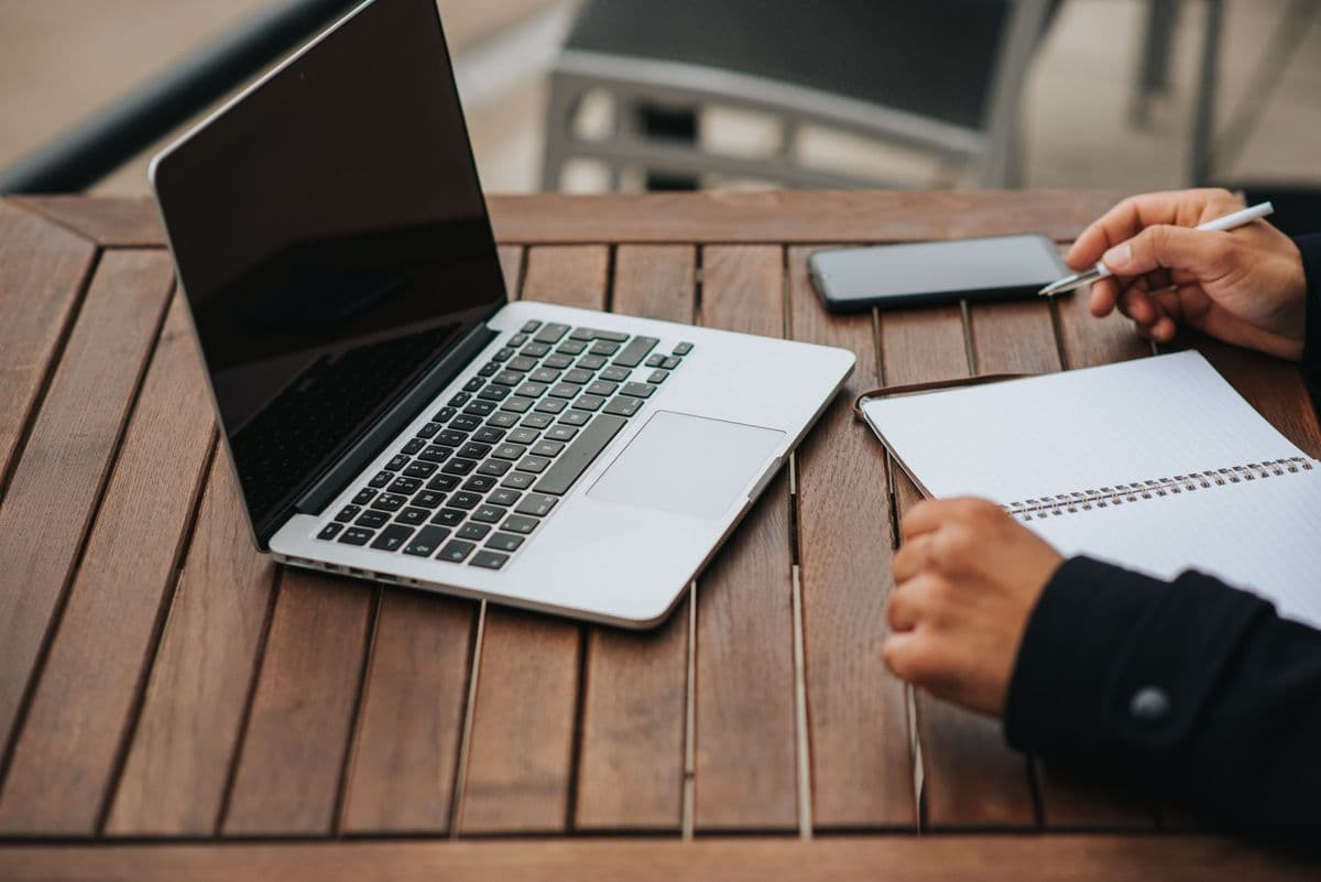 Freelancer organizando tarefas de vários clientes em um notebook na mesa de home office.