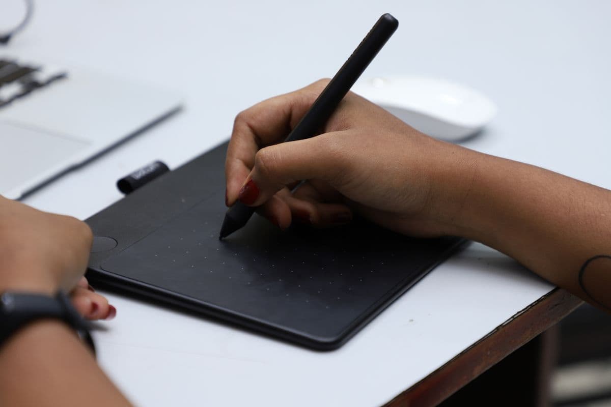 Ilustradora trabalhando em uma mesa com tablet gráfico, lápis e computador