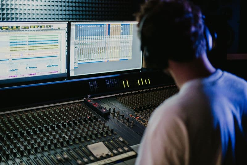 Freelancer locutor: como começar com voice over Sound engineer working with mixing console and monitors in a modern recording studio.