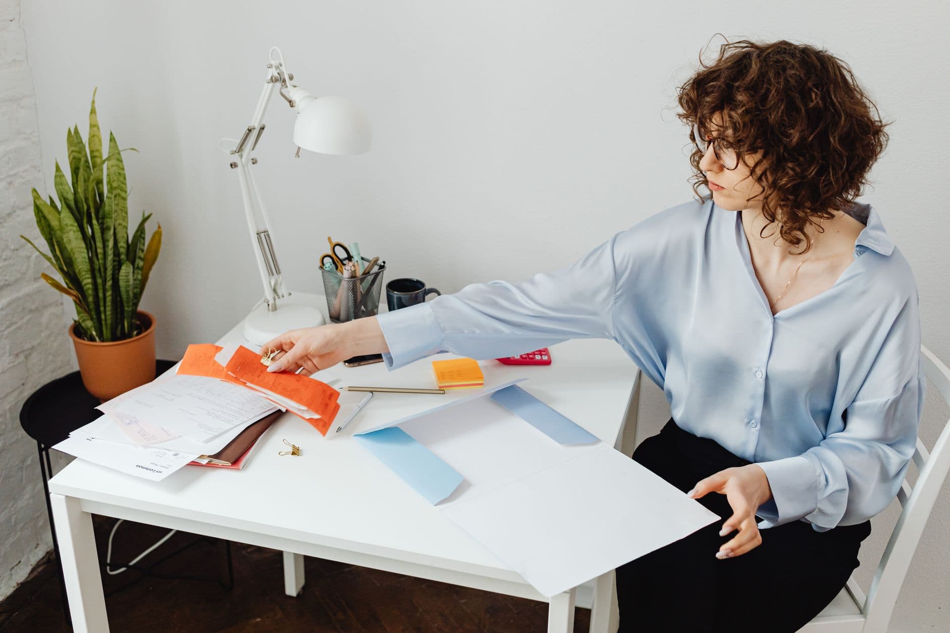Freelancer ou CLT remoto: qual escolher? A woman organizing papers at her desk, working in a bright office environment.