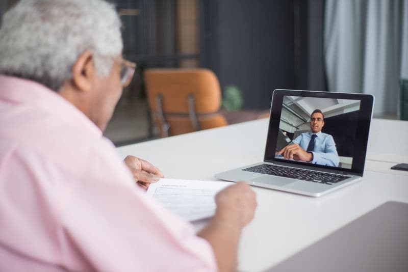 Freelancer: como precificar pelo valor entregue Senior discussing business on a video call with a consultant on a laptop.