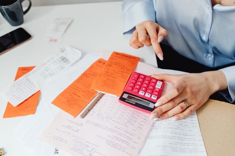 Freelancer: recibo ou nota fiscal? Entenda a diferença Businesswoman calculates expenses using receipts and calculator at desk. Ideal for finance, accounting themes.