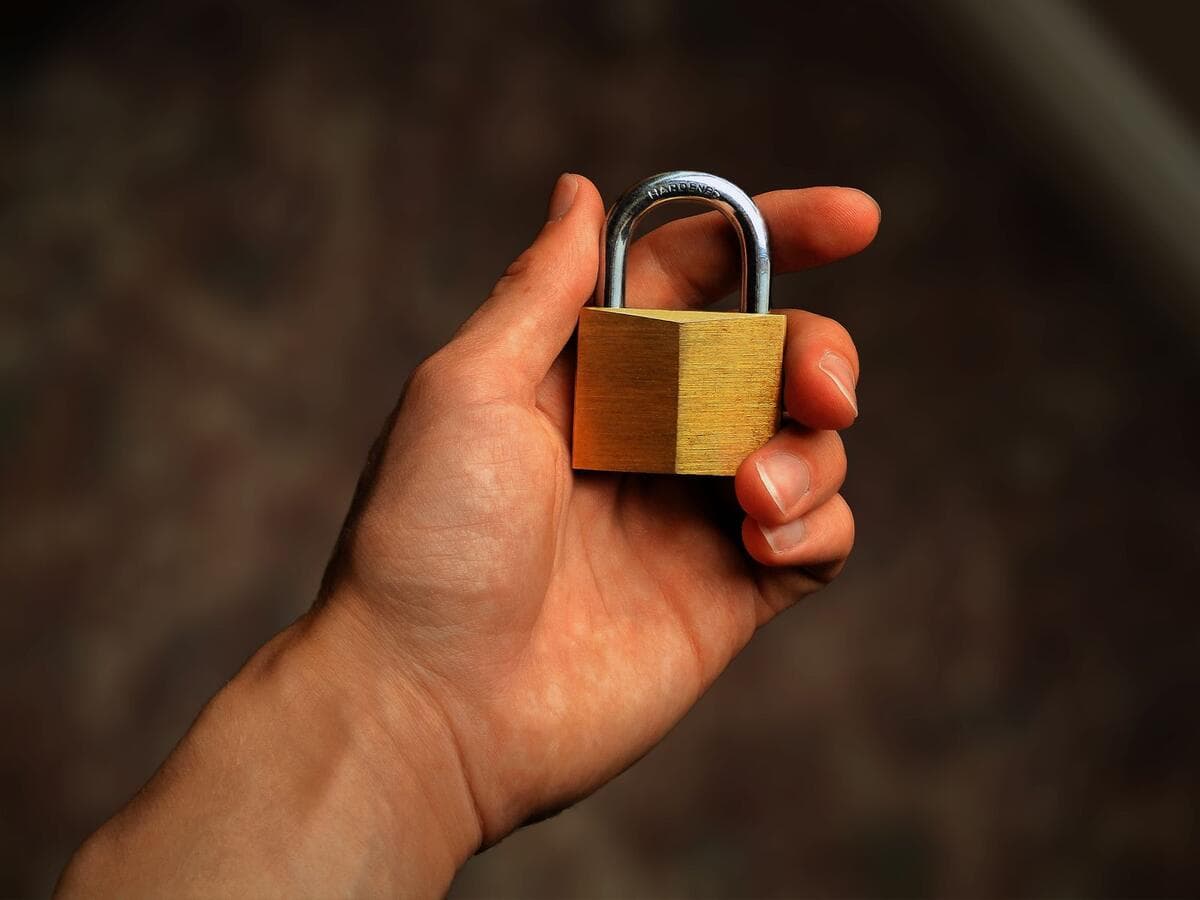 Passo a passo para migrar sem travar o trabalho Mão segurando um cadeado de latão, símbolo de segurança digital