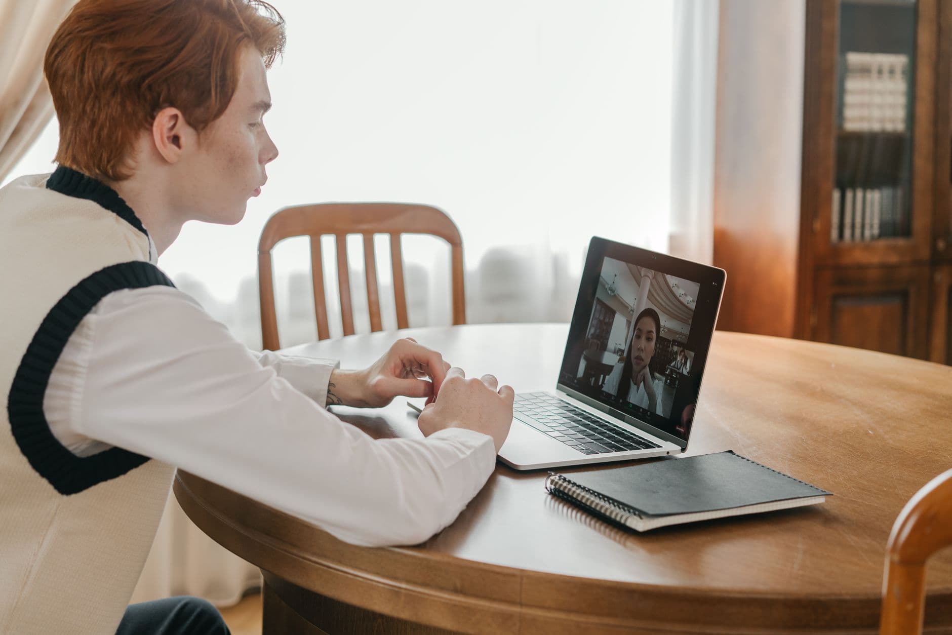 Gestão de equipe remota para líderes iniciantes Young man engaged in a video call on a laptop at home, indicating remote communication.