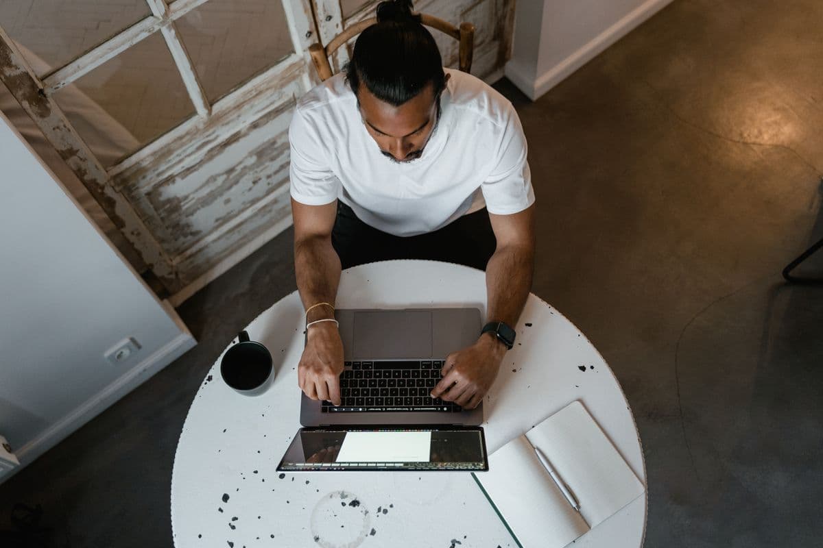 Pessoa escrevendo em um notebook em uma mesa de home office