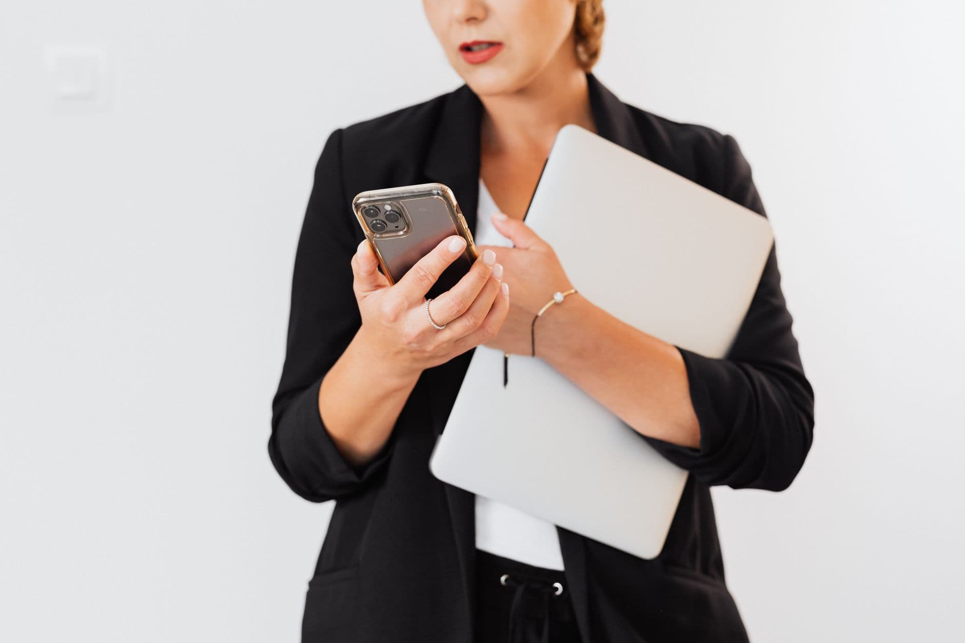 Golpe de vaga home office: como identificar Close-up of a businesswoman holding a laptop and smartphone indoors.