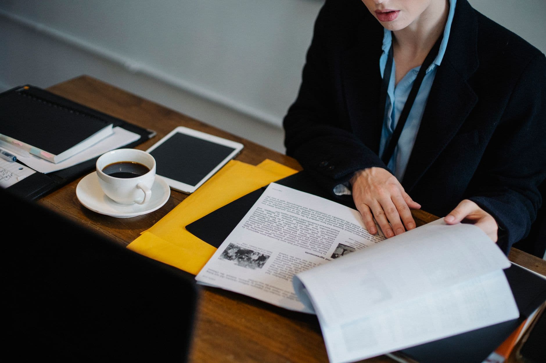 Como filtrar vagas remotas no Indeed High angle of crop faceless businesswoman in formal clothes sitting at table with tablet and hot coffee and looking through documents