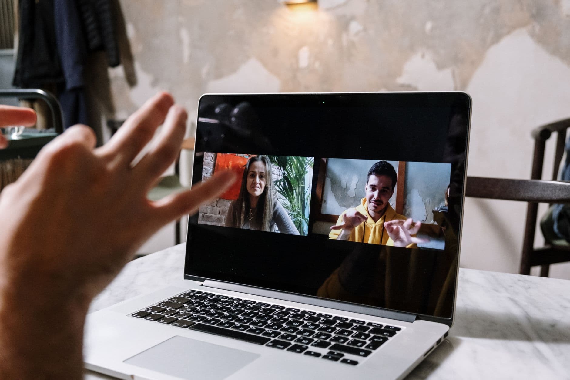 LGPD no trabalho remoto: o que muda Hands gesturing during a video call on a laptop screen, showing two people in a virtual meeting.