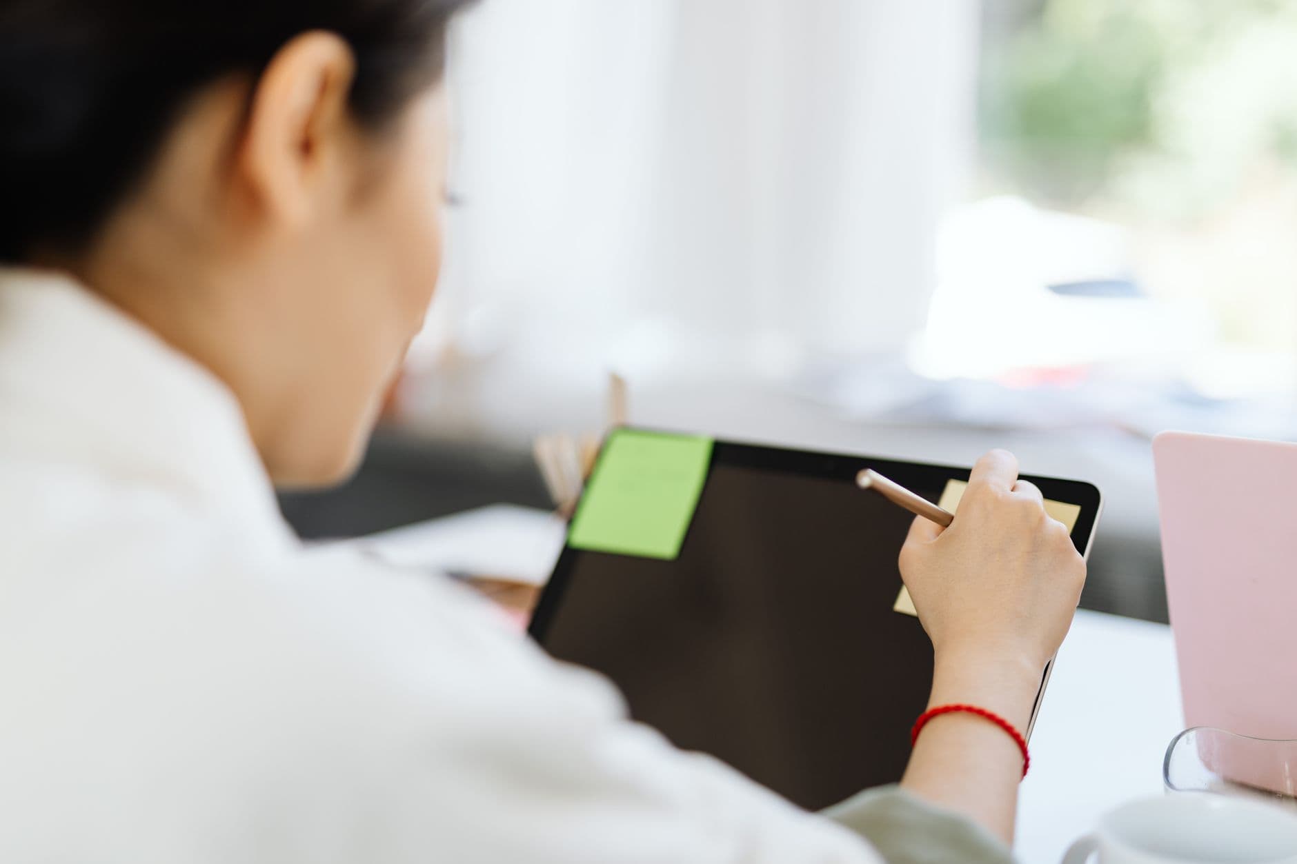 Método Eisenhower no home office: como priorizar tarefas A woman using a stylus on a tablet in a modern office setting.